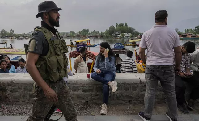An Indian tourist woman talk to her cell phone as Jammu and Kashmir Special Operation Group (SOG) personnel patrol at a Dal Lake in Srinagar, Indian controlled Kashmir,Tuesday, April. 22, 2025. (AP Photo/Mukhtar Khan)
