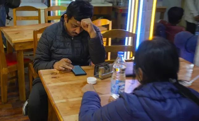 Anshuman Gaikwad, an Indian tourist browsing his phone at a restaurant after he was stopped from heading to Pahalgam in South Kashmir after assailants indiscriminately opened fired at tourists visiting Pahalgam, Indian controlled Kashmir, Tuesday, April 22, 2025.(AP Photo/Dar Yasin)