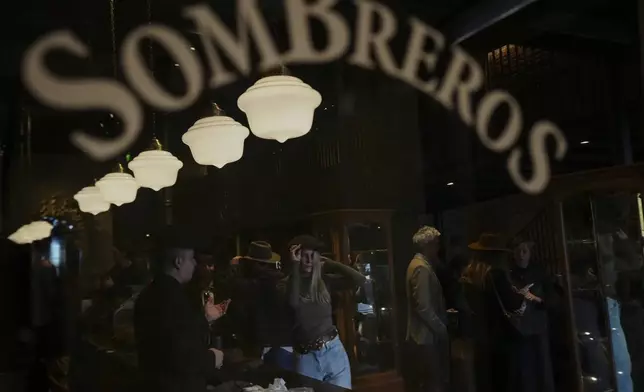 A customer tries on a hat at “Donde Golpea el Monito” hat shop and museum, in Santiago, Chile, Friday, April 3, 2025, that preserves a hat-making tradition dating back to 1915. (AP Photo/Esteban Felix)