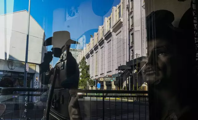 An employee takes a work break at the "Donde Golpea el Monito" hat shop and museum, which preserves a hat-making tradition for more than a century, in Santiago, Chile, Thursday, April 3, 2025. (AP Photo/Esteban Felix)