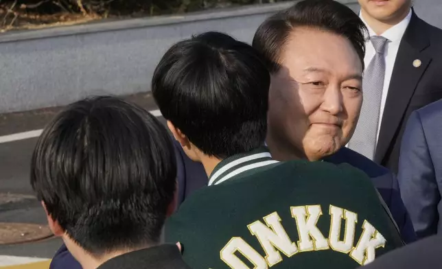 Recently ousted South Korean President Yoon Suk Yeol is greeted by a college student before he leaves the presidential residence in Seoul, South Korea, Friday, April 11, 2025. (AP Photo/Ahn Young-joon, Pool)