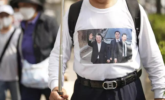 A supporter of recently removed South Korean President Yoon Suk Yeol wearing a dress with an image of Yoon stands near his private residence in Seoul, South Korea, Friday, April 11, 2025. (AP Photo/Lee Jin-man)