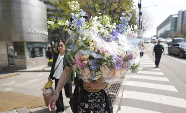 A supporter of recently removed South Korean President Yoon Suk Yeol carries flowers near Yoon's private residence in Seoul, South Korea, Friday, April 11, 2025. (AP Photo/Lee Jin-man)