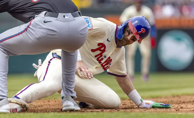 Philadelphia Phillies' Bryce Harper is safe on a pickoff attempt before Miami Marlins first baseman Matt Mervis can make the tag in the third inning of a baseball game, Saturday, April 19, 2025, in Philadelphia. (AP Photo/Laurence Kesterson)