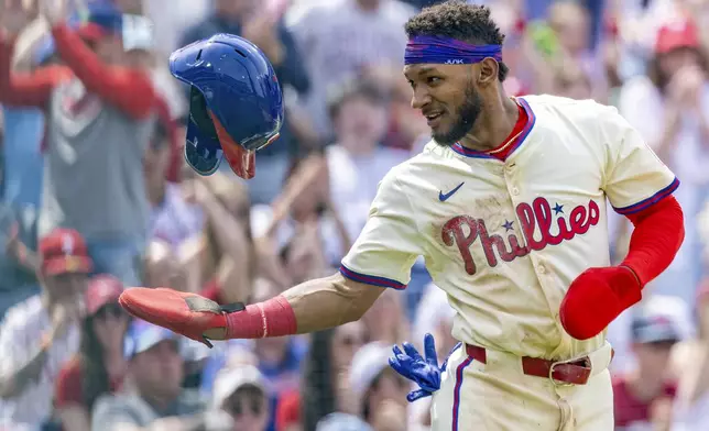 Philadelphia Phillies' Johan Rojas tosses his helmet after scoring on an RBI double by Bryson Stott in the fourth inning of a baseball game against the Miami Marlins, Saturday, April 19, 2025, in Philadelphia. (AP Photo/Laurence Kesterson)