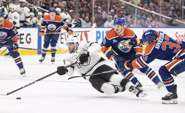 Los Angeles Kings' Alex Laferriere (14) falls while being pressured by Edmonton Oilers' Mattias Janmark (13) and Viktor Arvidsson (33) during the first period of Game 4 in an NHL hockey first-round playoff series in Edmonton, Alberta, Sunday, April 27, 2025. (Jason Franson/The Canadian Press via AP)
