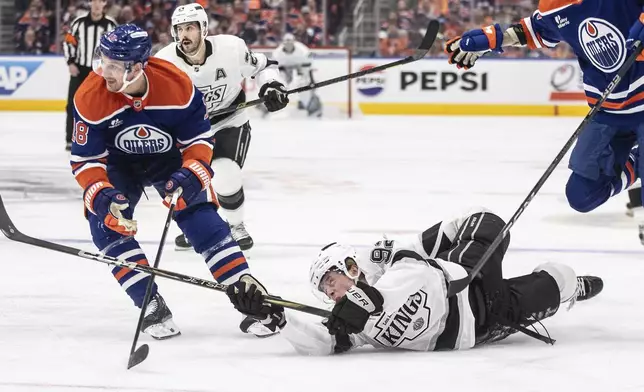 Los Angeles Kings' Brandt Clarke (92) is knocked down by Edmonton Oilers' Zach Hyman (18) during the first period of Game 4 in an NHL hockey first-round playoff series in Edmonton, Alberta, Sunday, April 27, 2025. (Jason Franson/The Canadian Press via AP)