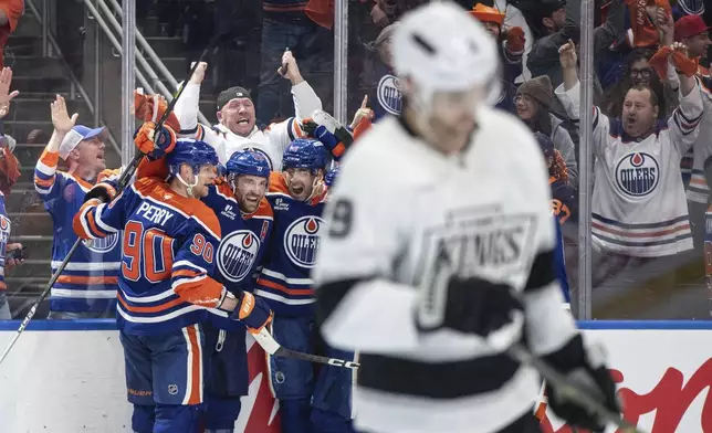 Edmonton Oilers' Corey Perry (90), Leon Draisaitl (29) and Evan Bouchard (2) celebrate the game-winning goal against the Los Angeles Kings in an overtime of an NHL playoff gamen in Edmonton on Sunday, April 27, 2025. (Jason Franson/The Canadian Press via AP)