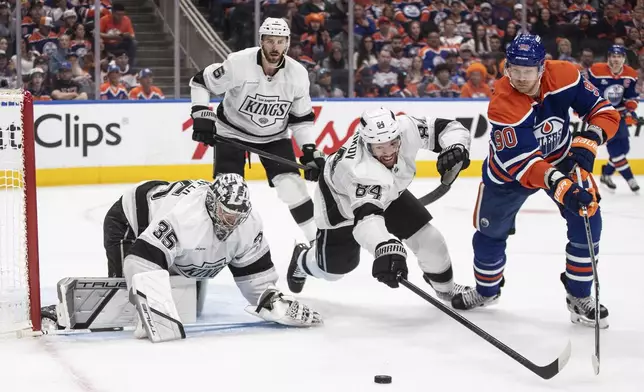 Los Angeles Kings goalie Darcy Kuemper (35) makes the save as Vladislav Gavrikov (84) and Edmonton Oilers' Corey Perry (90) reach for the rebound during the second period of an NHL playoff game in Edmonton on Sunday, April 27, 2025. (Jason Franson/The Canadian Press via AP)