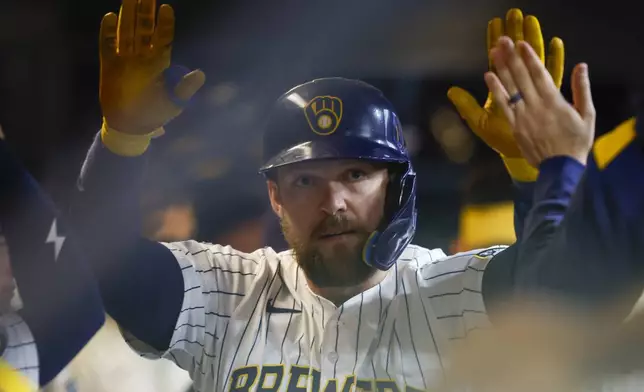Milwaukee Brewers' Rhys Hoskins receives high-fives in the dugout after his home run against the Athletics during the third inning of a baseball game, Sunday, April 20, 2025, in Milwaukee. (AP Photo/Jeffrey Phelps)