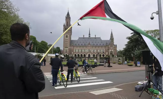 FILE - A lone demonstrator waves the Palestinian flag outside the Peace Palace, rear, housing the International Court of Justice, or World Court, in The Hague, Netherlands, on May 24, 2024. (AP Photo/Peter Dejong, File)