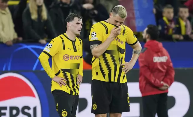 Dortmund's Niklas Suele, right, and Dortmund's Pascal Gross react at the end of the Champions League quarterfinals second leg soccer match between Borussia Dortmund and Barcelona, at the Signa-Iduna Park in Dortmund, Germany, Tuesday, April 15, 2025. (AP Photo/Martin Meissner)