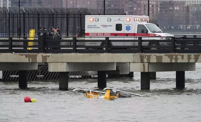 First responders stand on a pier at the scene where a helicopter crashed into the Hudson River, Thursday, April 10, 2025, in Jersey City, N.J. (AP Photo/Seth Wenig)