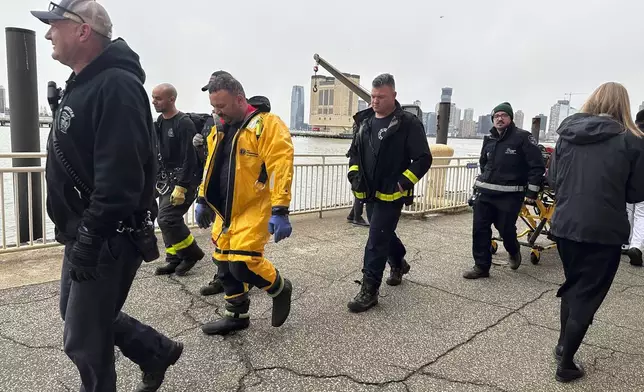 First responders walk along Pier 40, Thursday, April 10, 2025, in New York, across from where a helicopter went down in the Hudson River in Jersey City, N.J. (AP Photo/Jennifer Peltz)