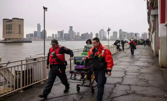 The New York City Fire Department (FDNY) personnels carry a stretcher at Pier 40, where a helicopter went down in the Hudson River between Manhattan and the New Jersey waterfront, Thursday, April 10, 2025, in New York. (AP Photo/Yuki Iwamura)