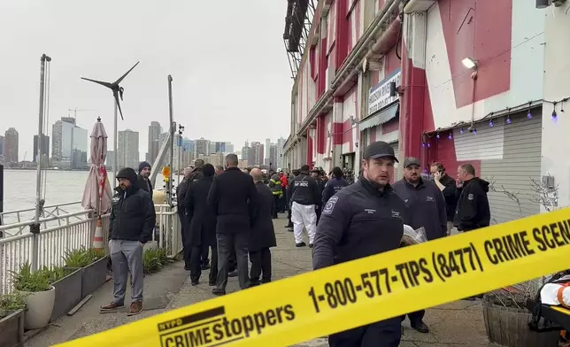 First responders walk along Pier 40, Thursday, April 10, 2025, in New York, across from where a helicopter went down in the Hudson River in Jersey City, N.J. (AP Photo/Jennifer Peltz)