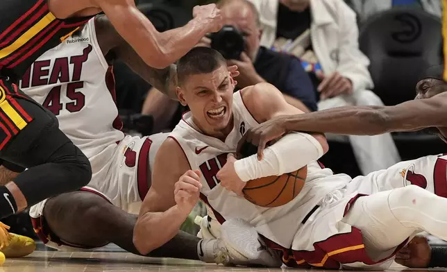 Miami Heat guard Tyler Herro (14) fights for the ball in overtime of an NBA play-in tournament basketball game against the Atlanta Hawks, Friday, April 18, 2025, in Atlanta. (AP Photo/Brynn Anderson)