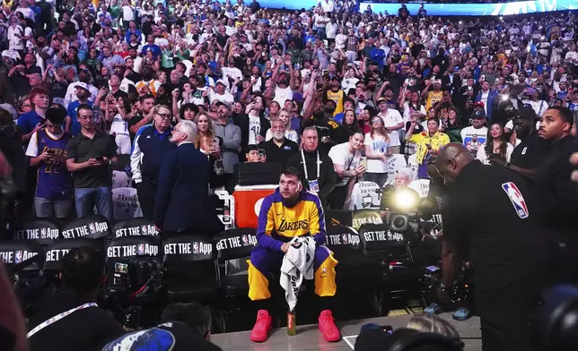 Los Angeles Lakers' Luka Doncic sits on the bench looking up at a video that was played in the arena as a tribute to the former Mavericks player before an NBA basketball game against the Dallas Mavericks in Dallas, Wednesday, April 9, 2025. (AP Photo/LM Otero)