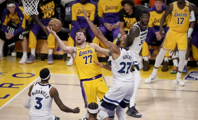 Los Angeles Lakers guard Luka Doncic (77) goes to the basket against Minnesota Timberwolves center Rudy Gobert (27) and forward Jaden McDaniels (3) during the second half of Game 2 of an NBA basketball first-round playoff in Los Angeles, Tuesday, April 22, 2025. (AP Photo/Eric Thayer)