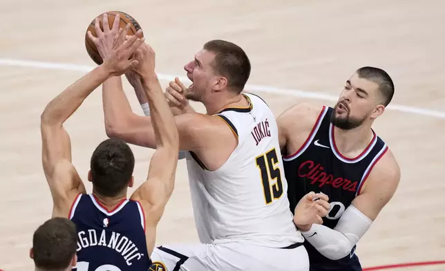 Denver Nuggets center Nikola Jokic, center, shoots as Los Angeles Clippers guard Bogdan Bogdanovic, left, and center Ivica Zubac defend during the second half in Game 3 of an NBA basketball first-round playoff series Thursday, April 24, 2025, in Inglewood, Calif. (AP Photo/Mark J. Terrill)