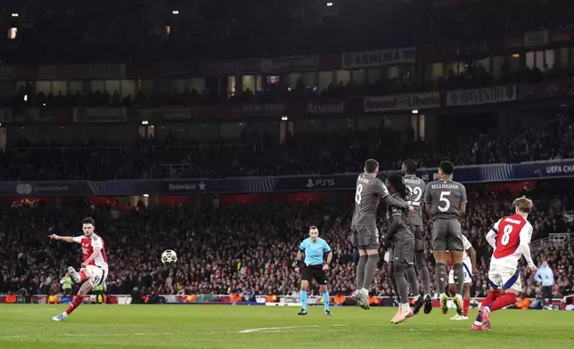 Arsenal's Declan Rice, left, scores his side's opening goal during the Champions League quarterfinal first leg soccer match between Arsenal and Real Madrid at the Emirates Stadium in London, Tuesday, April 8, 2025. (John Walton/PA via AP)