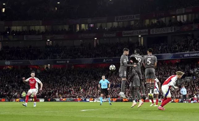 Arsenal's Declan Rice, left, scores his side's opening goal during the Champions League quarterfinal first leg soccer match between Arsenal and Real Madrid at the Emirates Stadium in London, Tuesday, April 8, 2025. (John Walton/PA via AP)
