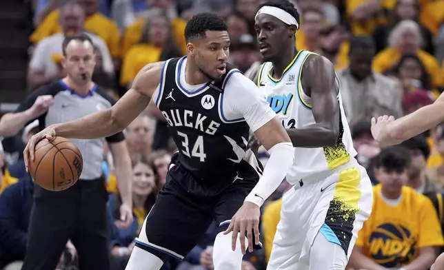 Milwaukee Bucks' Giannis Antetokounmpo (34) dribbles as Indiana Pacers' Pascal Siakam defends during the first half of a first-round NBA basketball playoff game, Saturday, April 19, 2025, in Indianapolis. (AP Photo/Michael Conroy)