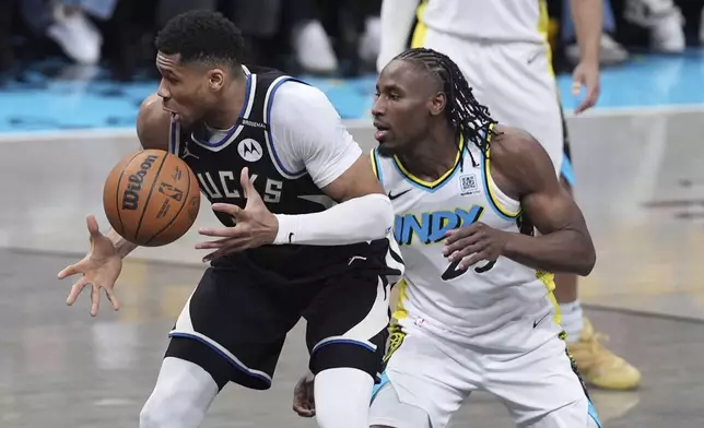 Milwaukee Bucks' Giannis Antetokounmpo, left, tries to keep control of the ball as Indiana Pacers' Aaron Nesmith, right, defends during the first half of a first-round NBA basketball playoff game, Saturday, April 19, 2025, in Indianapolis. (AP Photo/Michael Conroy)