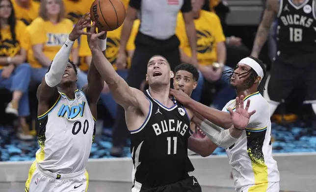 Milwaukee Bucks' Brook Lopez (11) reaches for a loose ball along with Indiana Pacers' Bennedict Mathurin (00) and Myles Turner, right, during the first half of a first-round NBA basketball playoff game, Saturday, April 19, 2025, in Indianapolis. (AP Photo/Michael Conroy)