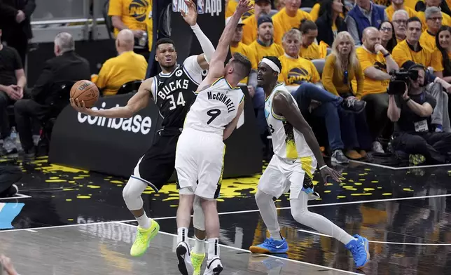 Milwaukee Bucks' Giannis Antetokounmpo (34) looks to pass as Indiana Pacers' T.J. McConnell (9) and Pascal Siakam defend during the second half of a first-round NBA basketball playoff game, Saturday, April 19, 2025, in Indianapolis. (AP Photo/Michael Conroy)