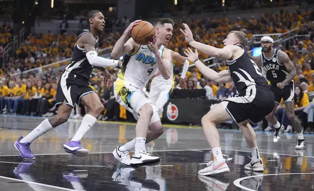 Indiana Pacers' T.J. McConnell (9) heads to the basket as Milwaukee Bucks' Kevin Porter Jr., left, and AJ Green, right, defend during the first half of a first-round NBA basketball playoff game, Saturday, April 19, 2025, in Indianapolis. (AP Photo/Michael Conroy)