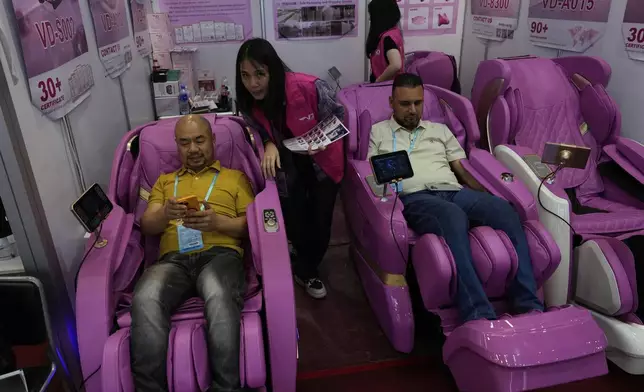 Visitors try out massage chairs at the 137th Canton Fair in Guangzhou in southern China's Guangdong province, Tuesday, April 15, 2025. (AP Photo/Ng Han Guan)