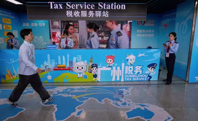 A man walks by the Guangzhou Tax Service booth at the 137th Canton Fair in Guangzhou in southern China's Guangdong province on Tuesday, April 15, 2025. (AP Photo/Ng Han Guan)