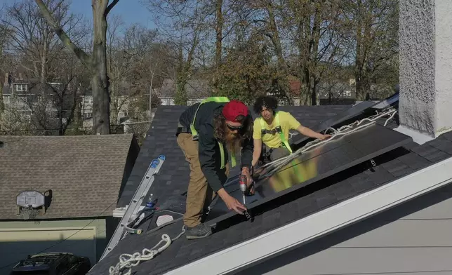 Theodore Tanczuk, left, and Brayan Santos, right, of solar installer YellowLite, put solar panels on the roof of a home in Lakewood, Ohio, Thursday, April 17, 2025. (AP Photo/Sue Ogrocki)