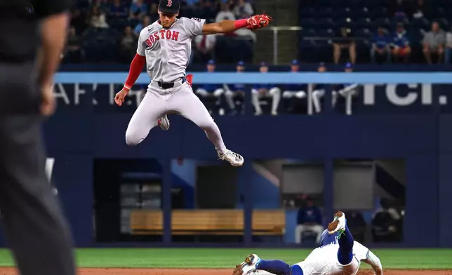 Toronto Blue Jays shortstop Bo Bichette, right, slides into second base with a steal ahead of a tag by Boston Red Sox second baseman Kristian Campbell during the first inning of a baseball game in Toronto on Tuesday, April 29, 2025. (Jon Blacker/The Canadian Press via AP)