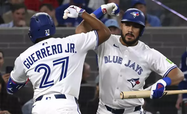 Toronto Blue Jays' Vladimir Guerrero Jr (27) celebrates with Anthony Santander, right, after hitting a two-run home run against the Boston Red Sox in the third inning of a baseball game in Toronto on Tuesday, April 29, 2025. (Jon Blacker/The Canadian Press via AP)