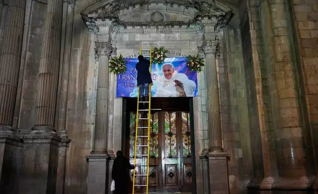 A worker places a banner of the late Pope Francis on the front of Cathedral Nuestra Senora de La Paz, Bolivia, Monday, April 21, 2025. (AP Photo/Juan Karita)
