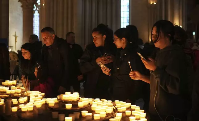 People light candles inside Notre Dame cathedral Monday, April 21, 2025 in Paris. (AP Photo/Thibault Camus)