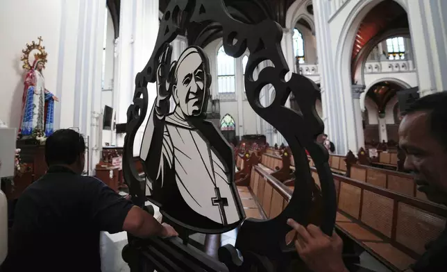 Church workers prepare an ornament depicting Pope Francis ahead of a mass at the Cathedral of Our Lady of the Assumption, which was visited by Pope Francis in 2024, in Jakarta, Indonesia, Monday, April 21, 2025. (AP Photo/Achmad Ibrahim)