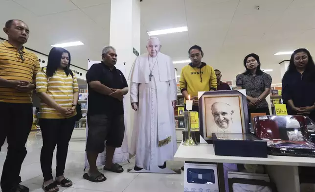 Employees of Kanisius Catholic bookstore pray with a cutout of Pope Francis in Yogyakarta, Indonesia, Monday, April 21, 2025. (AP Photo/Slamet Riyadi)