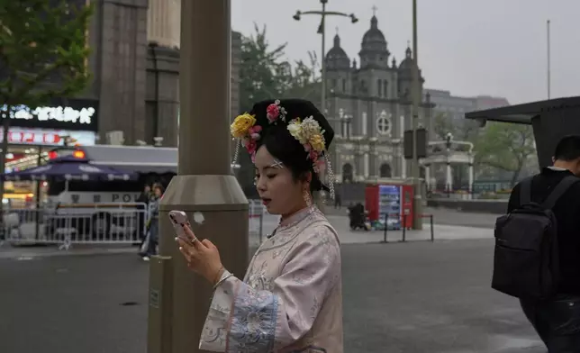 A woman in traditional costume past by the Wangfujing Catholic Church also know as East Church in Beijing, Monday, April 21, 2025. (AP Photo/Ng Han Guan)