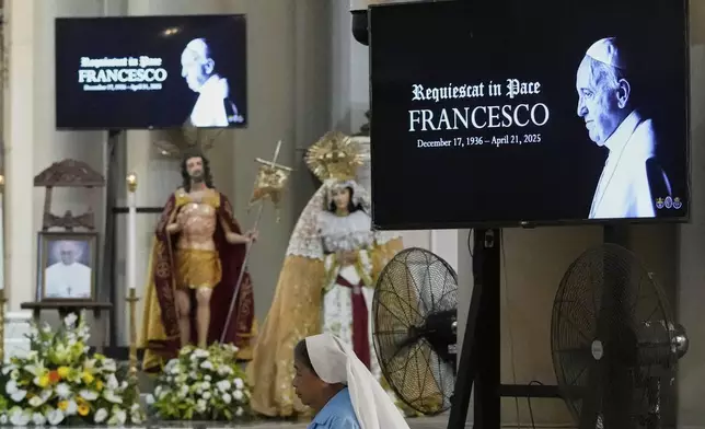 Images of the late Pope Francis is shown as a Catholic nun walks inside a church in Quezon city, Philippines Monday, April 21, 2025. (AP Photo/Aaron Favila)