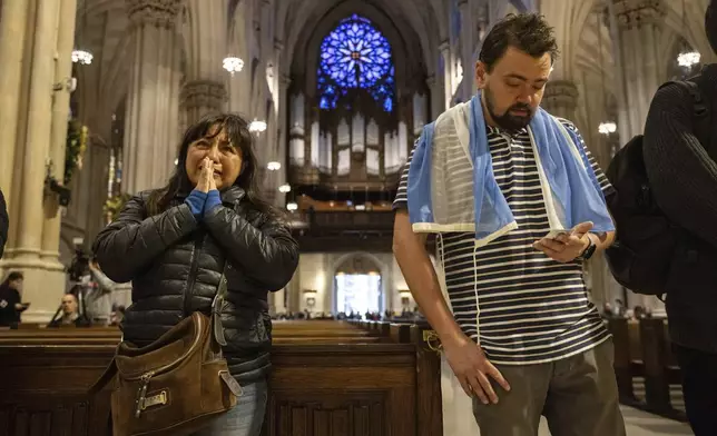 Parishioners pray in front of a picture of Pope Francis at St. Patrick's Cathedral, Monday, April 21, 2025, in New York. (AP Photo/Yuki Iwamura)