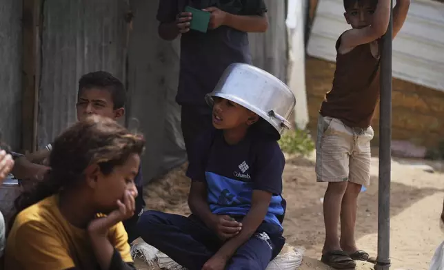 Palestinian children wait to receive donated food at a distribution center in Khan Younis, Gaza Strip, Monday, April 21, 2025. (AP Photo/Abdel Kareem Hana)