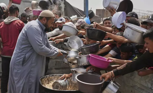 Palestinian children receive donated food at a distribution center in Khan Younis, Gaza Strip, Monday, April 21, 2025. (AP Photo/Abdel Kareem Hana)