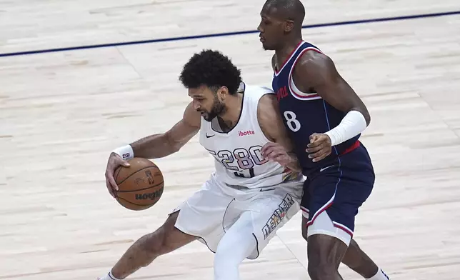 Denver Nuggets guard Jamal Murray, left, works the ball to the basket as Los Angeles Clippers guard Kris Dunn defends in the first half of Game 5 of an NBA basketball playoff series Tuesday, April 29, 2025, in Denver. (AP Photo/David Zalubowski)