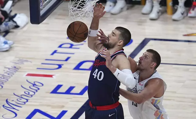 Los Angeles Clippers center Ivica Zubac, left, dunks the ball for a basket as Denver Nuggets center Nikola Jokic defends in the first half of Game 5 of an NBA basketball playoff series Tuesday, April 29, 2025, in Denver. (AP Photo/David Zalubowski)