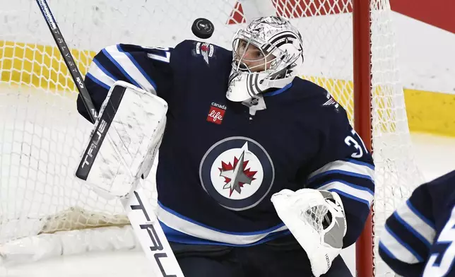 Winnipeg Jets goaltender Connor Hellebuyck (37) makes a save against a St. Louis Blues shot during the third period of Game 2 of a first-round NHL hockey playoff series in Winnipeg, Manitoba, Monday April 21, 2025. (Fred Greenslade/The Canadian Press via AP)