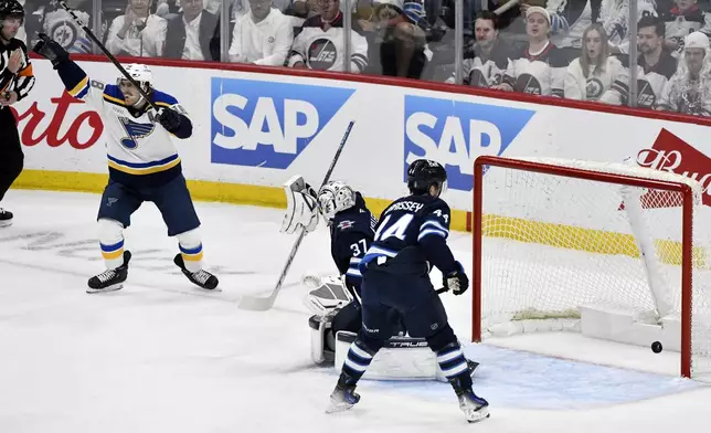 St. Louis Blues' Robert Thomas (18) celebrates a goal on on Winnipeg Jets goaltender Connor Hellebuyck (37) on a shot by Jimmy Snuggerud, not shown, during the first period of an NHL playoff game in Winnipeg, Monday April 21, 2025. (Fred Greenslade/The Canadian Press via AP)