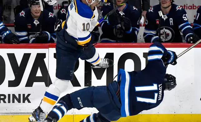 St. Louis Blues' Brayden Schenn (10) checks Winnipeg Jets' Adam Lowry (17) during the first period of Game 2 of a first-round NHL hockey playoff series in Winnipeg, Manitoba, Monday April 21, 2025. (Fred Greenslade/The Canadian Press via AP)